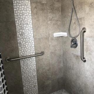 A modern shower with tiled walls and safety grab bars.