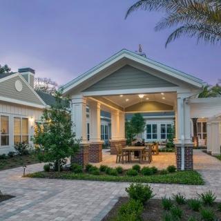 A beautifully landscaped home with an inviting outdoor patio lit up in the evening.