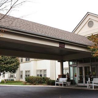 The exterior view of a building entrance with an awning and driveway.