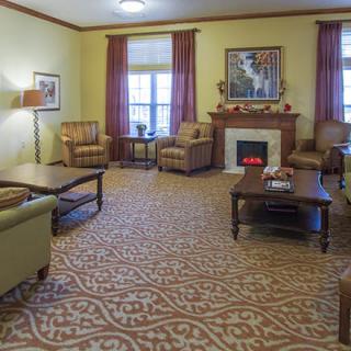 A cozy living room with a fireplace, armchairs, and a patterned carpet.