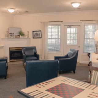 A cozy living room with blue chairs, a fireplace, and large windows.