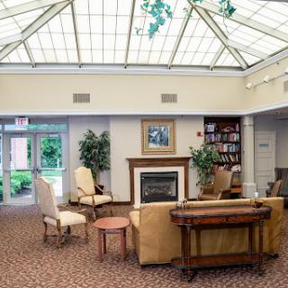 A cozy lounge area featuring a fireplace and comfortable furnishings, bathed in natural light from the glass ceiling.