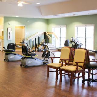 A spacious rehabilitation exercise room featuring fitness equipment and comfortable seating.
