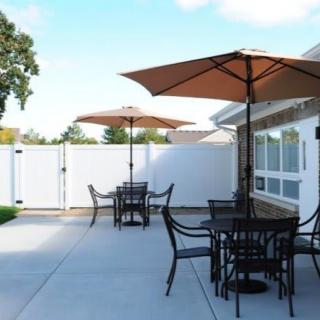 An outdoor patio with tables, chairs, and umbrellas under a clear sky.