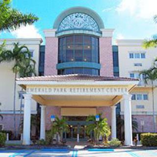 The entrance of a retirement center with palm trees and a modern architectural design.