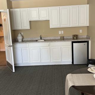 A kitchenette setup with white cabinets, a small sink, and a mini fridge.