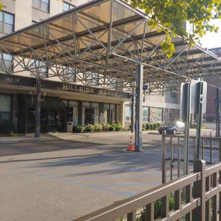 A modern building entrance with a covered walkway and a paved parking area.