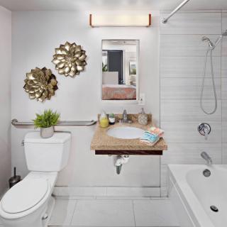 A contemporary bathroom featuring modern fixtures, decorative wall art, and a tiled shower area.