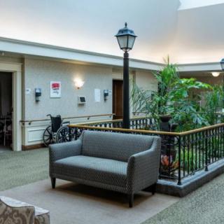A well-lit lobby area featuring a sofa and indoor plants next to a decorative lamp post.
