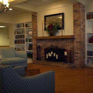 Cozy living room with a brick fireplace and shelves filled with books.