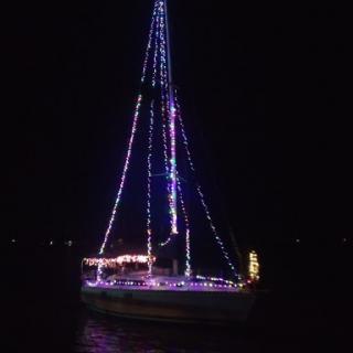 A beautifully decorated sailboat illuminated with colorful lights on a tranquil night.