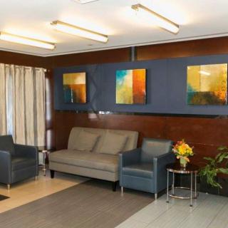 A modern living room with sofas, armchair, and abstract artwork on the wall.