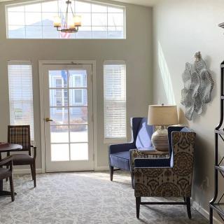 A bright and welcoming living room featuring large windows, elegant armchairs, and decorative elements.