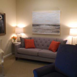 A cozy living room with a grey sofa, colorful cushions, and ambient lighting from lamps.