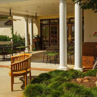 A cozy outdoor patio area with seating, plants, and columns.