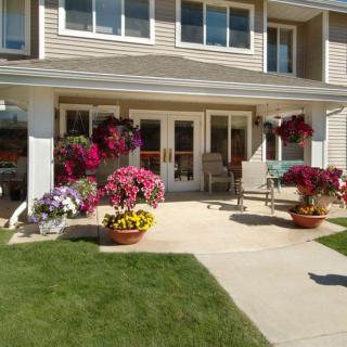 A cozy patio area adorned with vibrant flowers and comfortable seating in front of a house.