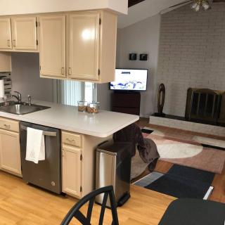 An open floor plan featuring a kitchen with beige cabinets and a living room with a fireplace and television.