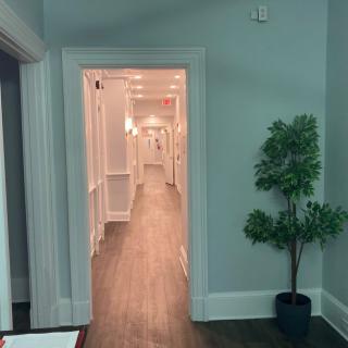 A view through a doorway into a long hallway with a potted plant nearby.