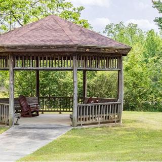 A wooden gazebo in a lush green park setting.