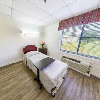 A simple and clean room with a single bed and a large window.