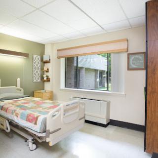 A well-lit hospital room featuring a patient bed and a view of the outside.