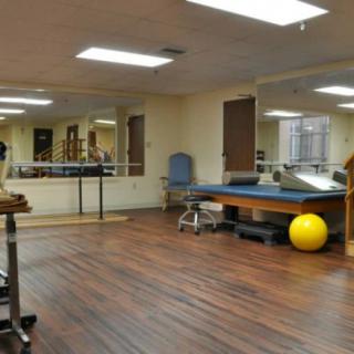 A physical therapy and rehabilitation room equipped with a treatment table, exercise ball, and ballet bar.