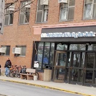 A view of a brick building showcasing its entrance, bicycles parked outside, and a bench for seating.