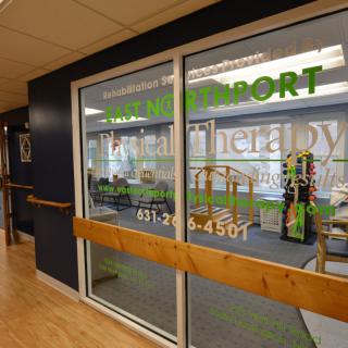 Entrance to a physical therapy and rehabilitation center with exercise equipment visible inside.