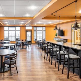 A modern dining area featuring orange walls, wooden flooring, and ample seating arrangements.