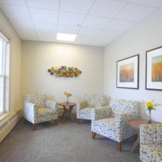 A cozy waiting room with patterned chairs and decorative art on the walls.
