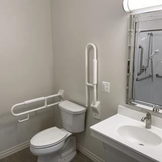 A modern, handicap-accessible bathroom with grab bars and a clean design.