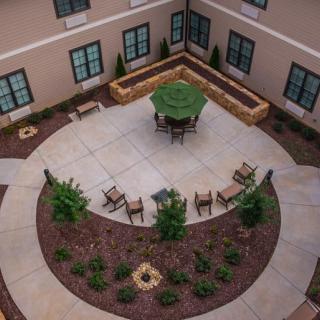 A beautifully landscaped courtyard with round patio seating and vibrant greenery.