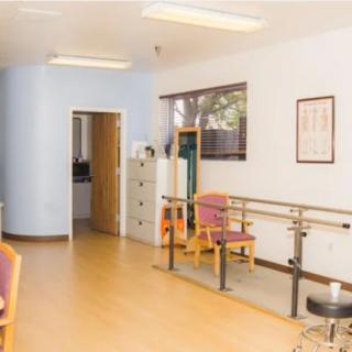 A physical therapy room equipped with parallel bars and chairs for rehabilitation exercises.