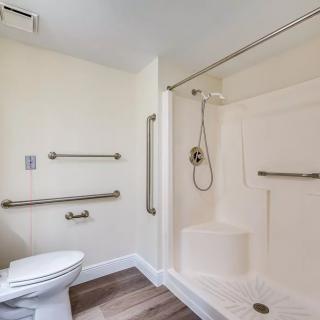 A modern, accessible bathroom featuring a shower with grab bars and a toilet.