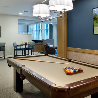 A well-lit recreation room featuring a pool table and a seating area.