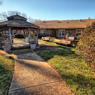 A peaceful garden with a gazebo and pathway leading to a building.