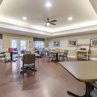 A spacious community dining area with tables and chairs, decorated with wall art and well-lit ceiling lights.