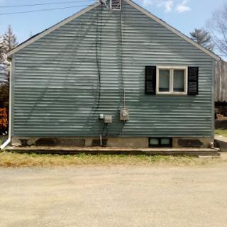 A side view of a residential house with blue siding and visible utility connections.