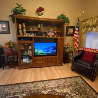 A cozy living room featuring an entertainment center with a television, bookshelves, and elegant decor.