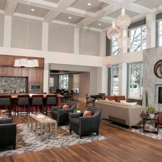 A spacious and modern open-concept living room with a view into the kitchen, featuring luxurious furniture and high ceilings.