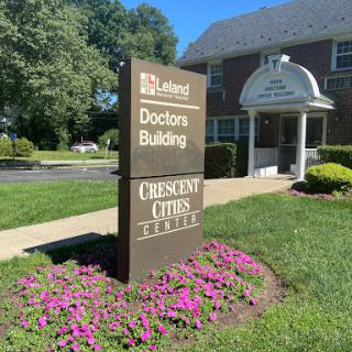 Sign for the Doctors Building and Crescent Club, surrounded by landscaped flowers.