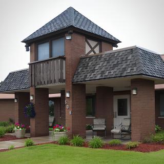 A modern brick house with a balcony and landscaped garden.