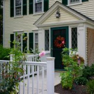 A charming house with a front porch and decorative wreath on the door, surrounded by lush greenery.