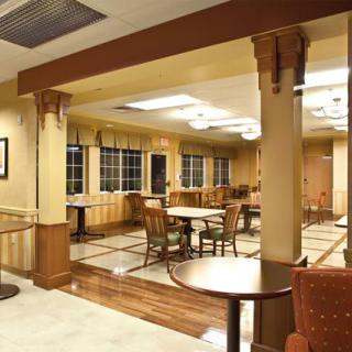 An empty dining area with neatly arranged tables and chairs, illuminated by overhead lighting.