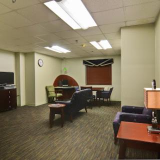 A modern office interior featuring a waiting area with couches and a desk.