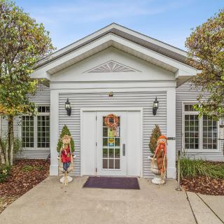 The front entrance of a white house with symmetrical design and neatly maintained landscaping.
