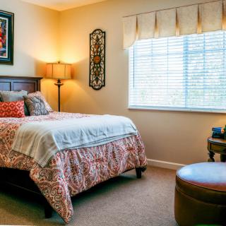 A cozy bedroom with a neatly made bed, warm lamp, and stylish decor.