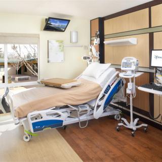 A modern hospital room equipped with medical devices and a comfortable bed.