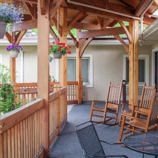 A cozy porch with wooden rocking chairs, hanging plants, and a covered roof.