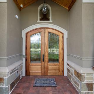 A stylish home entrance with a wooden arched front door and stone accents.